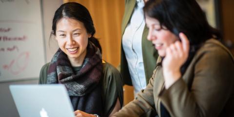 Two people looking at a laptop, smiling